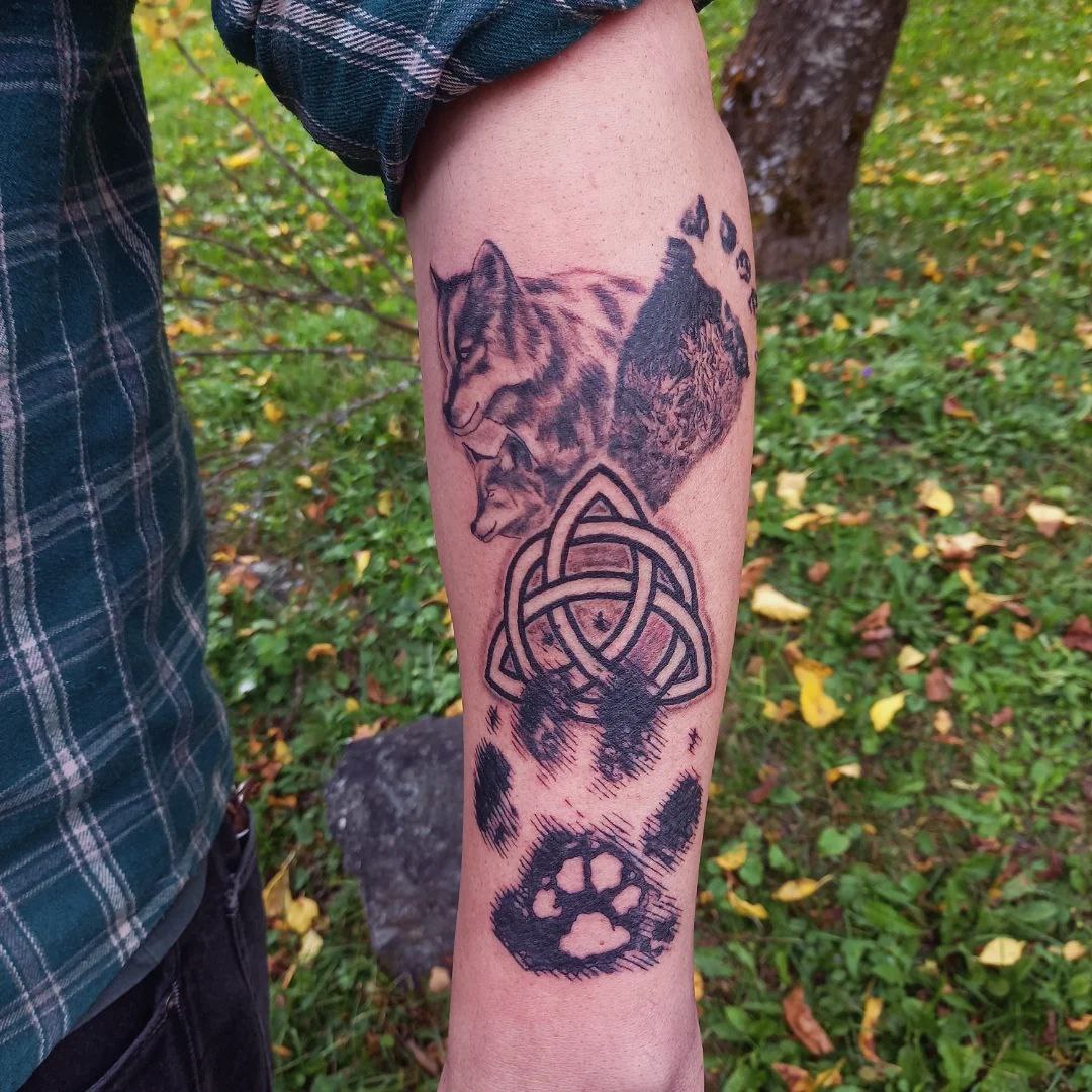 tatouage du petit loup, composé de pates de loup et de louveteau, d'un triskel, de la trace du pied de l'enfant,de deux loups réalistes, le tout armonieusement relié dans une composition moderne