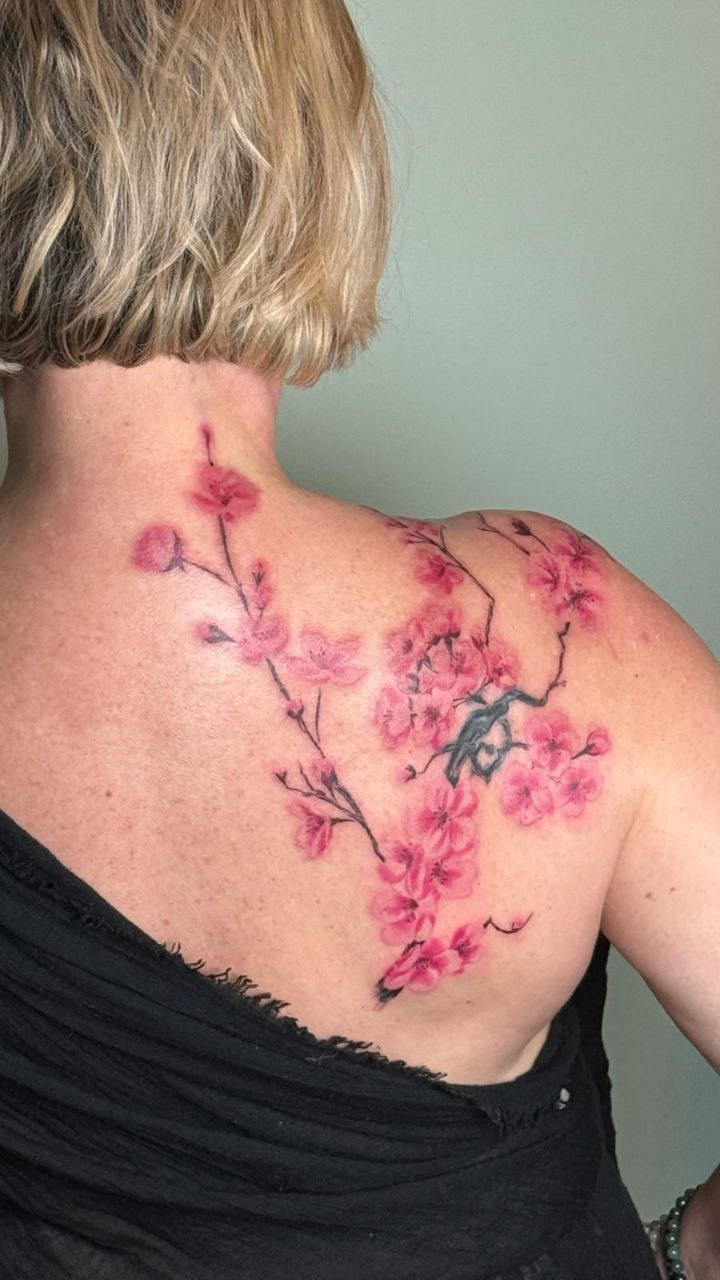 Tatouage cover d'une petite pièce dans le dos. devenu grande Branche de fleurs de cerisier délicatement colorées à la façon Sumi-e, sakura